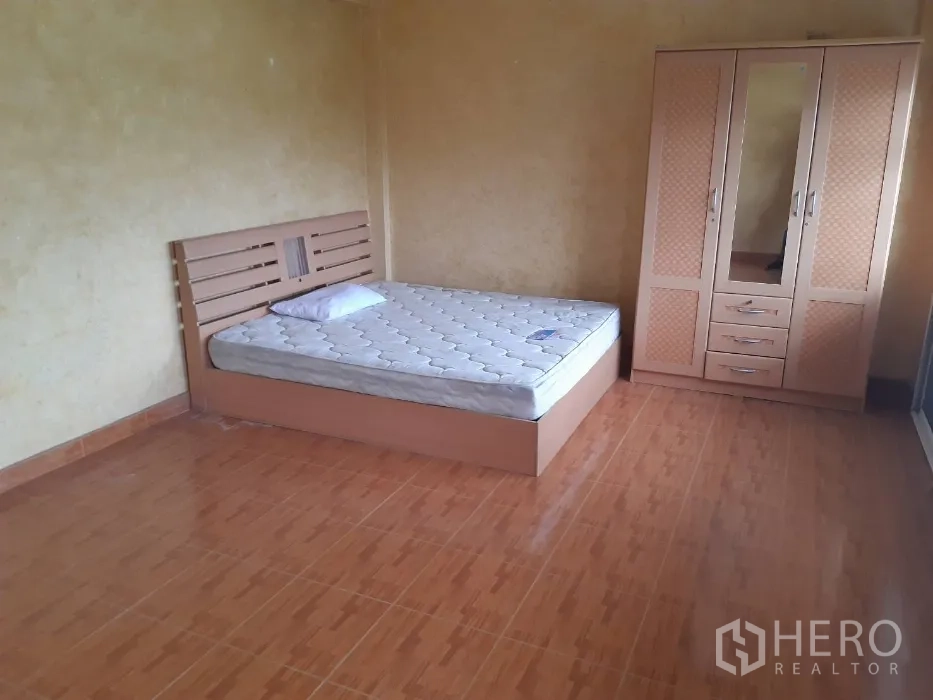 Townhouse for rent in Khlong Toei, Bangkok - Bright bedroom with tiled flooring, a bed and matching wardrobe.