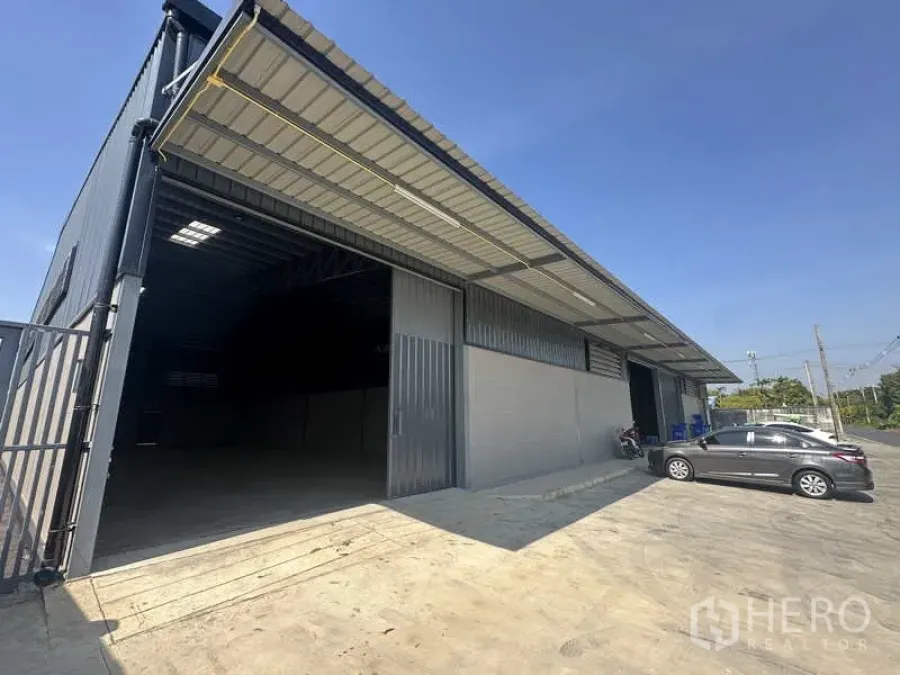 คลังสินค้า ให้เช่าในBang Bua Thong, Nonthaburi - ด้านหน้าโกดังโครงเหล็ก ประตูบานเลื่อนกว้าง มีหลังคากันสาดและลานจอด
