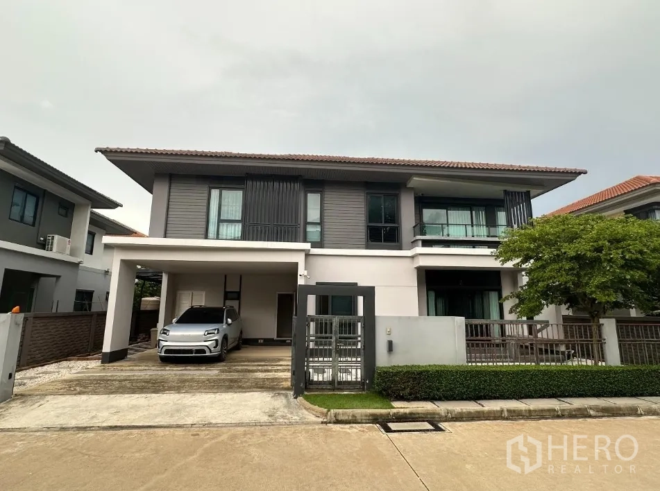 Detached House for rent in Lam Luk Ka, Pathum Thani - Modern two-storey façade with carport, gate and small front garden.