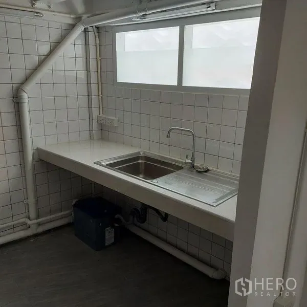 Shophouse for rent in Khlong Toei, Bangkok - Compact kitchenette with stainless sink, white tiled backsplash and frosted window.
