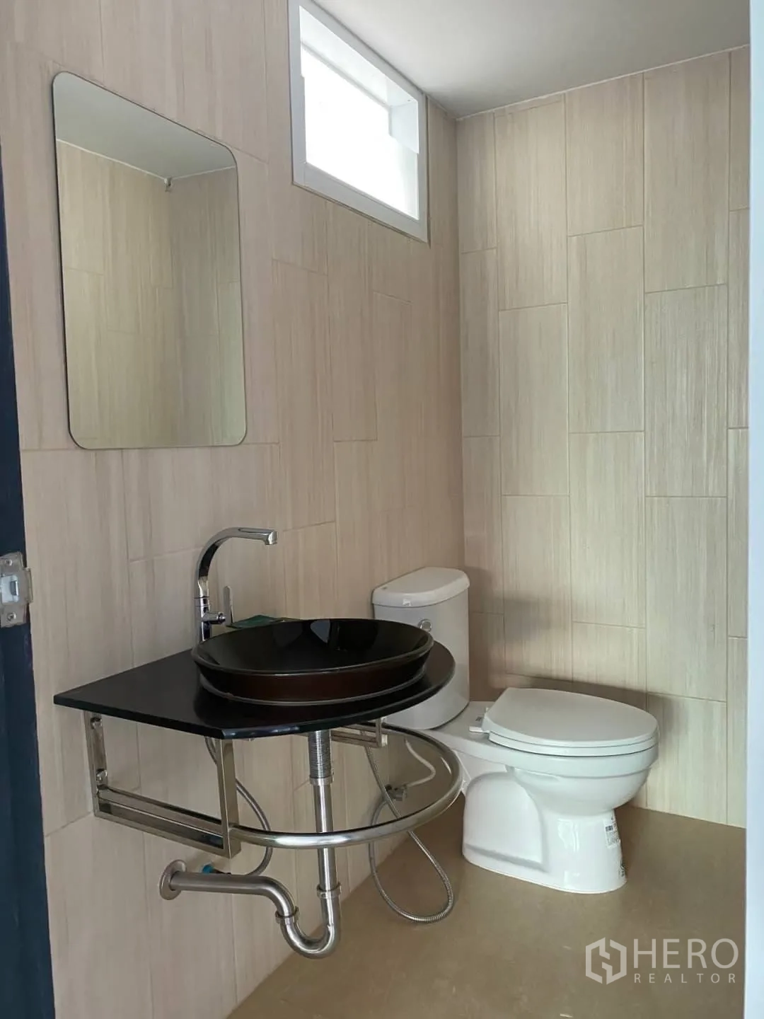 Home Office for sale - Guest bathroom finished with beige tiles, a black vessel sink, and toilet.