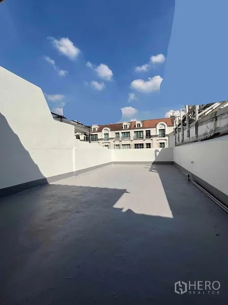 Home Office for rent in Khlong Toei, Bangkok - Large rooftop terrace with high privacy walls under a clear blue sky.