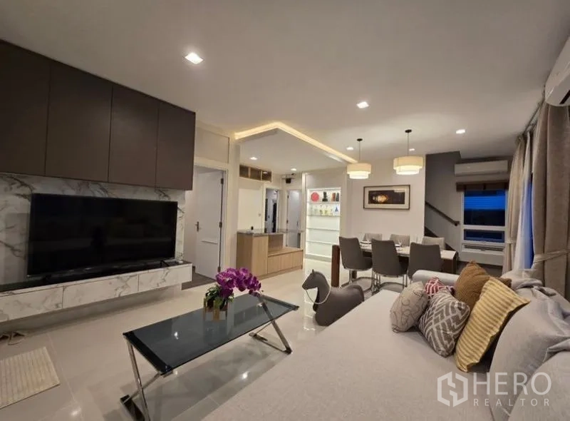 Detached House for rent - Open-plan living and dining area with large TV wall, sofa and pendant lighting.