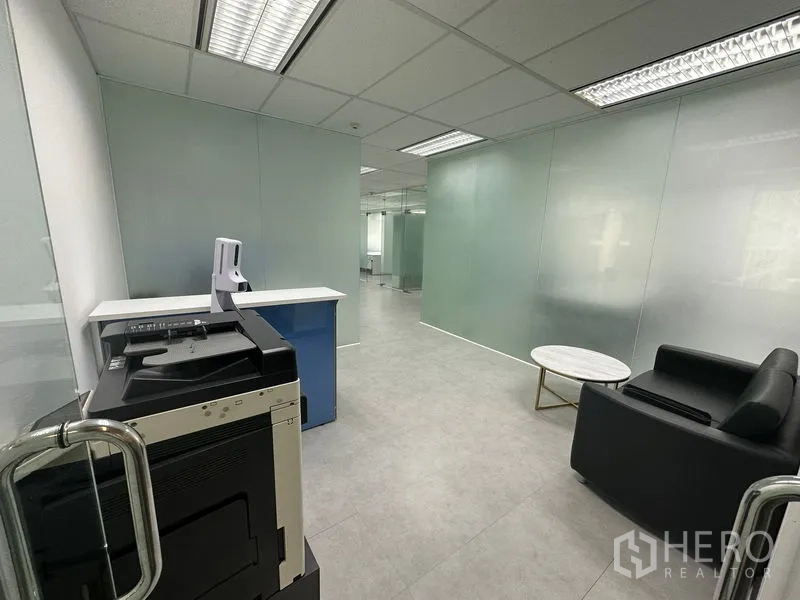 Office Space for rent - Hallway with printer station, frosted glass walls and a compact lounge seating area.