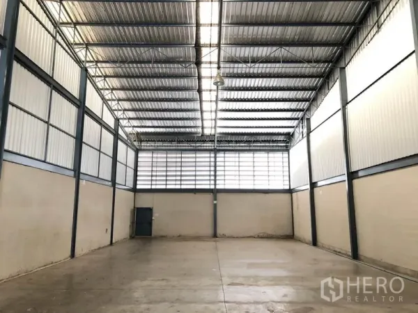 Warehouse for rent in Mueang Samut Prakan, Samut Prakan - Spacious warehouse interior with high steel truss roof, skylight panels and concrete floor.