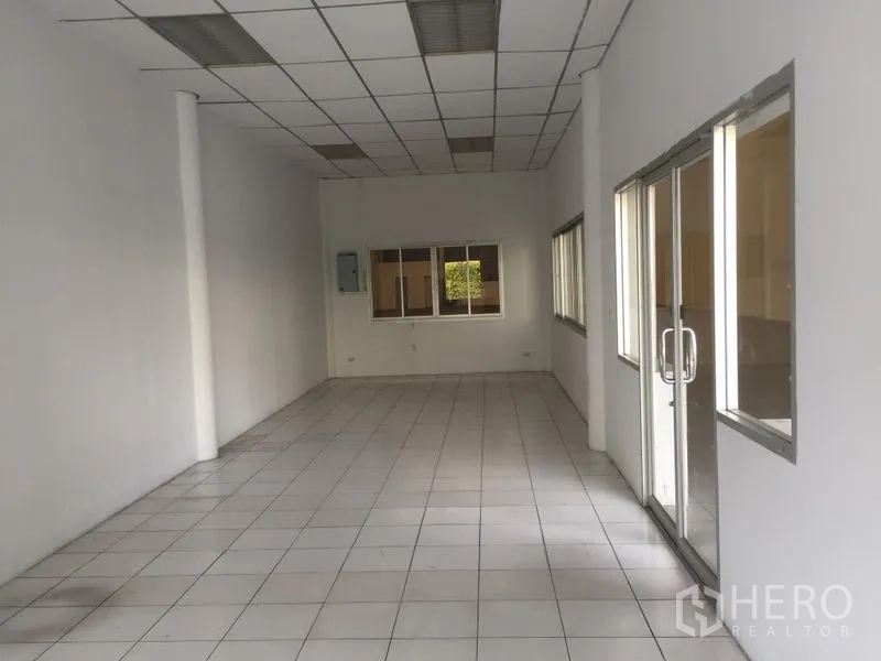 Factory for rent in Khlong Luang, Pathum Thani - Bright tiled office room with drop ceiling, glass sliding doors, and multiple windows inside the factory.