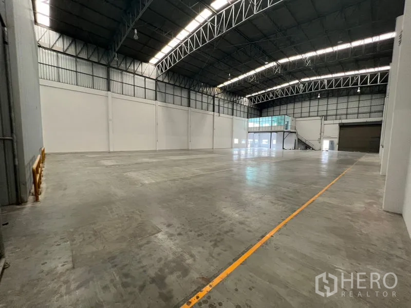 货栈 出租在Lat Krabang, Bangkok - 大面积清空地坪，标线清晰，远端为玻璃夹层办公室与装卸门。