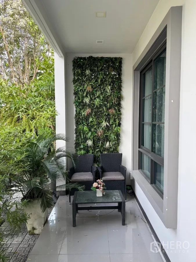 Detached House for sale in Mueang Pathum Thani, Pathum Thani - Cozy patio seating area with vertical garden wall and greenery.