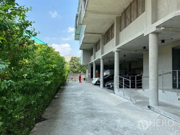 Home Office for rent or sale in Prawet, Bangkok - Long driveway with greenery and covered parking bays beneath the structure.