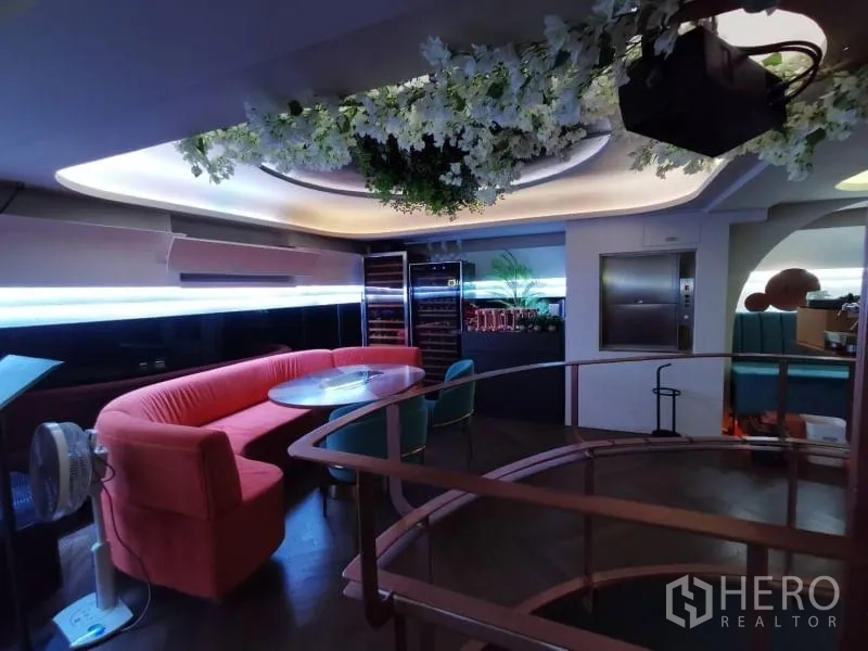 Retail Space for rent - Mezzanine nook with curved sofa, round table, wine coolers, and hanging flowers.