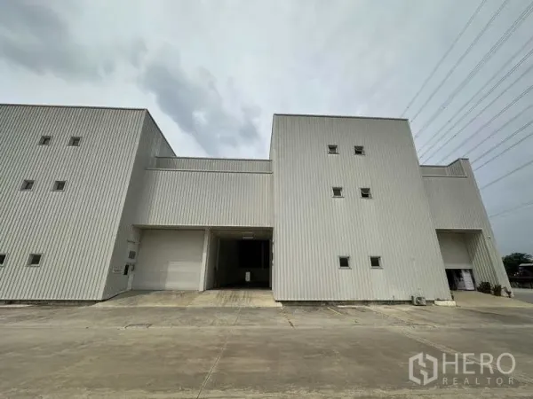 Factory for rent in Khlong Luang, Pathum Thani - Front elevation of steel-clad factory unit with large roller shutter and parking area.