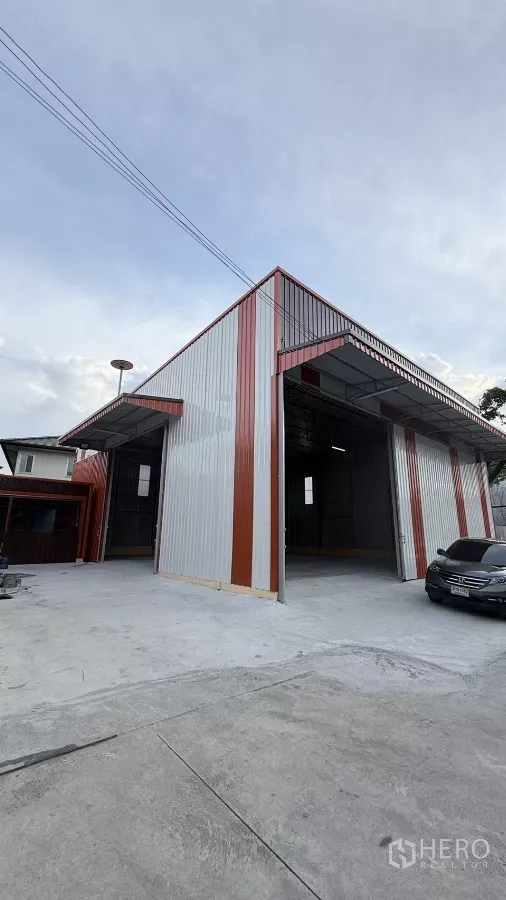 Warehouse for rent in Wang Thonglang, Bangkok - High-clearance steel warehouse exterior with twin wide sliding doors and a concrete yard.