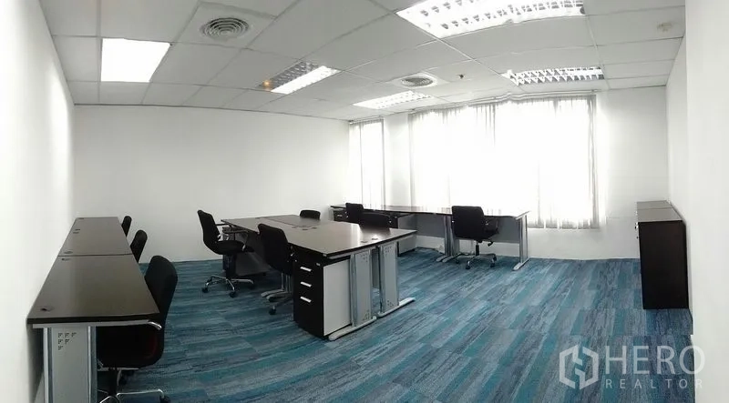Office Space for rent in Ratchathewi, Bangkok - Bright furnished office with multiple desks, rolling chairs, blue carpet and large windows.