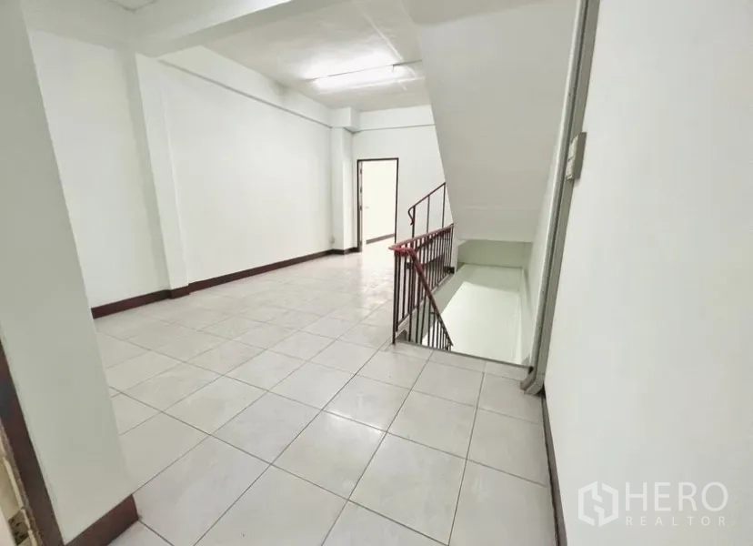 Shophouse for rent in Suan Luang, Bangkok - Upper-floor landing with tiled floors, white walls, and a stairwell.