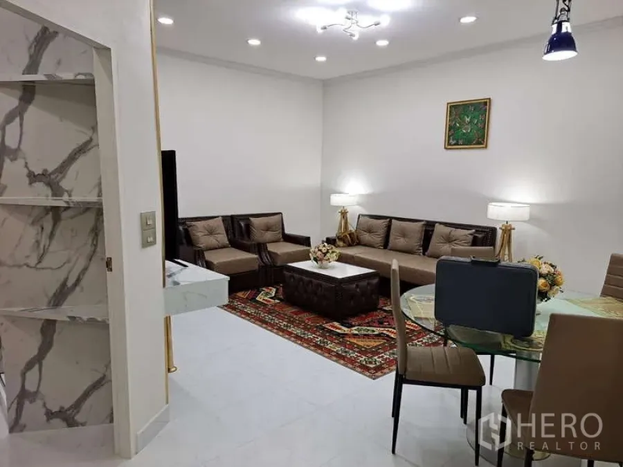 Condominium for rent in Khlong Toei, Bangkok - Open‑plan living and dining area with sofa set, round table and bright lighting.