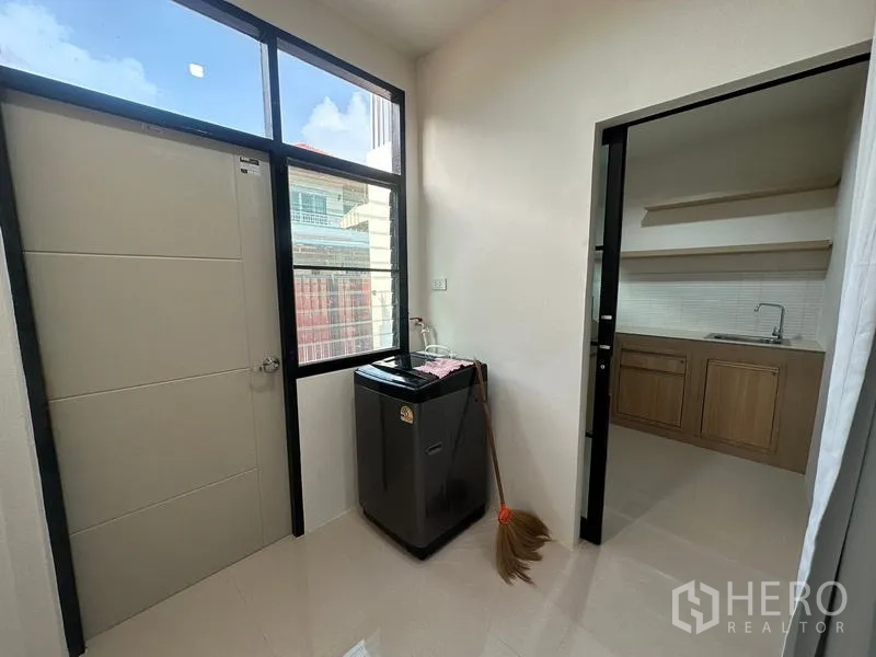 Townhouse for rent or sale in Phra Khanong, Bangkok - Compact separate kitchen with fridge, sink, cabinets and open shelves.