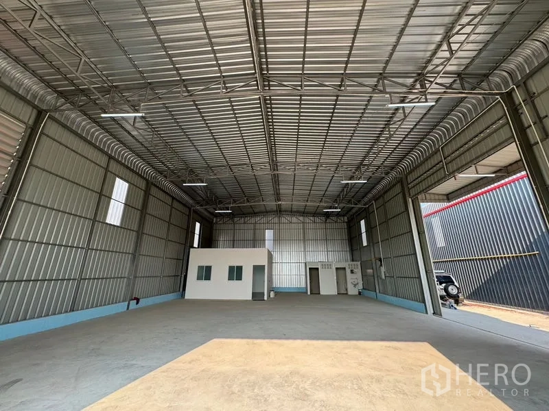 Warehouse for rent in Lam Luk Ka, Pathum Thani - Open storage hall with high ceiling, office pod and utility rooms at the rear.