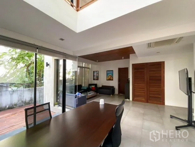 Townhouse for rent in Khlong Toei, Bangkok - Dining and lounge space with sliding glass doors opening to a decked terrace.