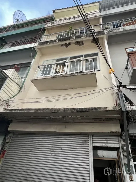 Shophouse for rent in Watthana, Bangkok - Street-facing multi-storey shophouse facade with balconies and a metal shopfront shutter in Bangkok.