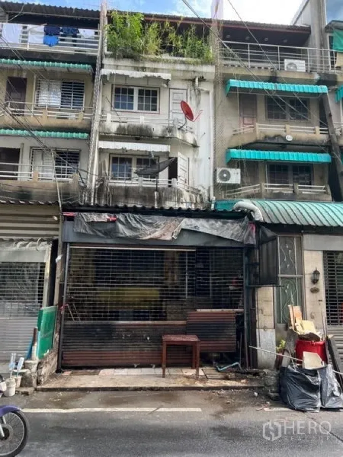 Shophouse for rent in Watthana, Bangkok - Four-storey shophouse facade with metal roller shutter and balconies in the Sukhumvit area of Bangkok.