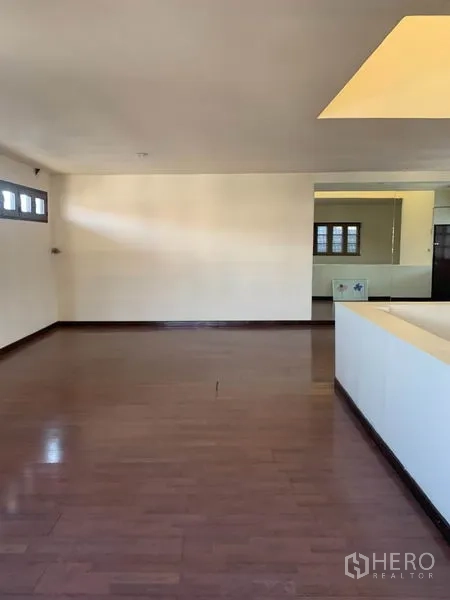 Townhouse for rent or sale in Phra Khanong, Bangkok - Open multipurpose room with wood floors, neutral walls and slim high windows.