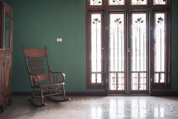 Townhouse for rent in Khlong Toei, Bangkok - Bright sitting area with rocking chair and tall glass doors