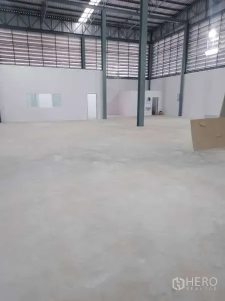 Warehouse for rent in Khlong Toei, Bangkok - Spacious warehouse interior with high steel roof, ventilation louvers, concrete floor and a small office room.