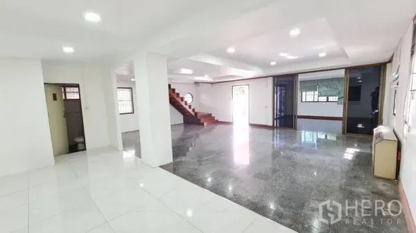 Detached House for rent in Lat Phrao, Bangkok - Bright open-plan living area with recessed lighting, mixed tile flooring and wooden staircase.