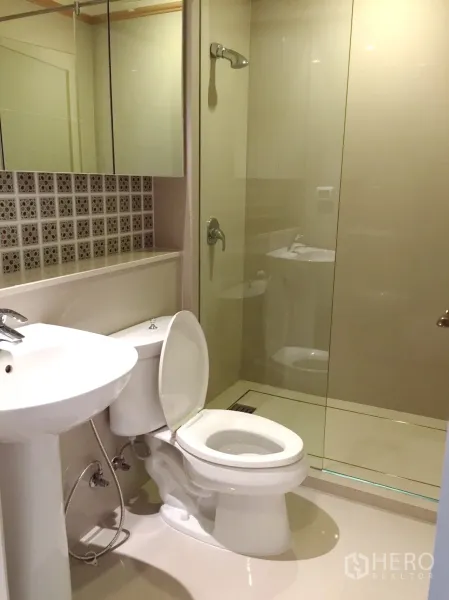 Condominium for rent in Khlong Toei, Bangkok - Modern bathroom with glass shower, white fixtures and mosaic accent tiles