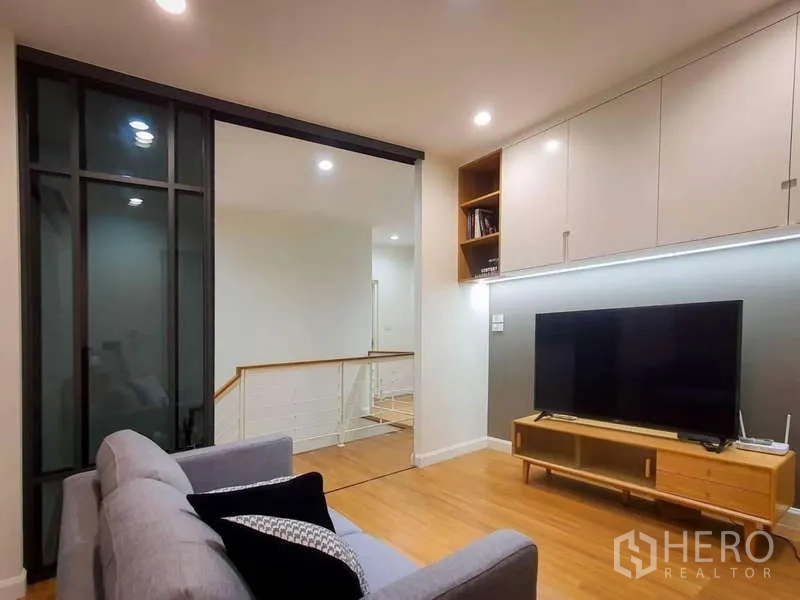 Detached House for rent in Sathon, Bangkok - Upstairs family lounge with sofa, TV wall, and a glass partition.