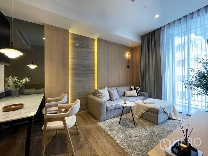 Condominium for rent or sale in Pathum Wan, Bangkok - Open-plan lounge and dining with marble breakfast bar, pendant lights, feature wall and tall windows.
