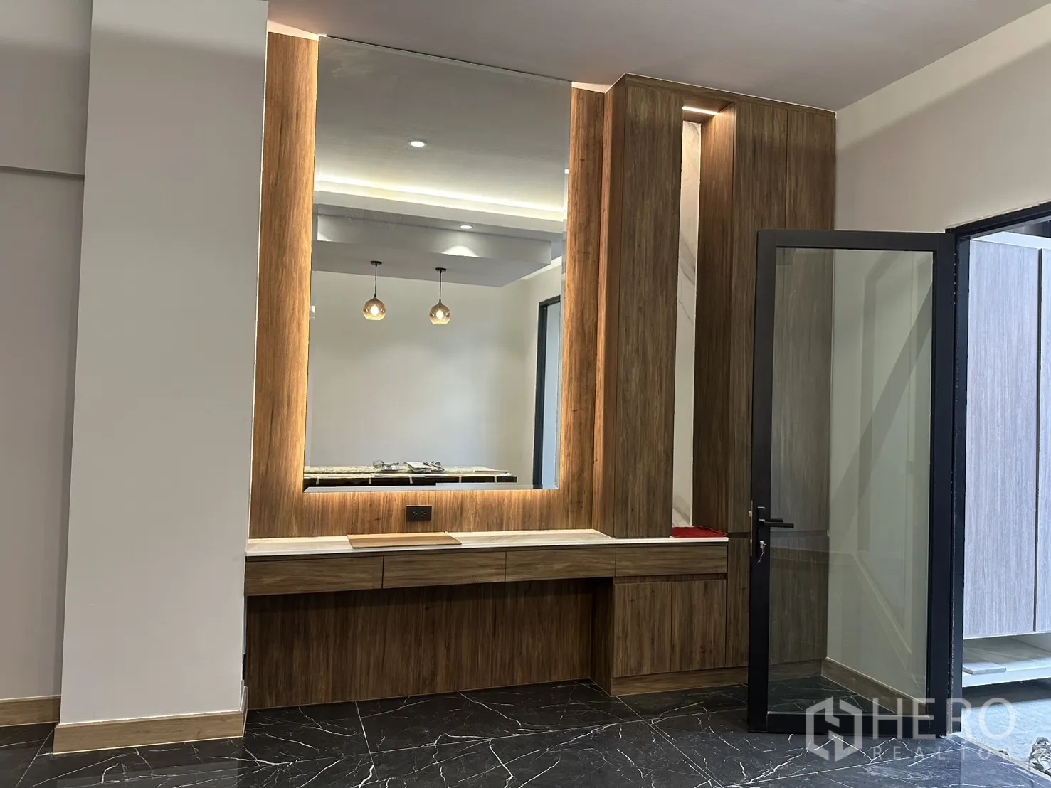 Home Office for rent in Watthana, Bangkok - Built-in wood feature wall with large backlit mirror beside a glass door.
