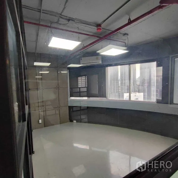 Office Space for rent in Watthana, Bangkok - Glass-enclosed room with bright ceiling panels, a curved window ledge and city outlook.