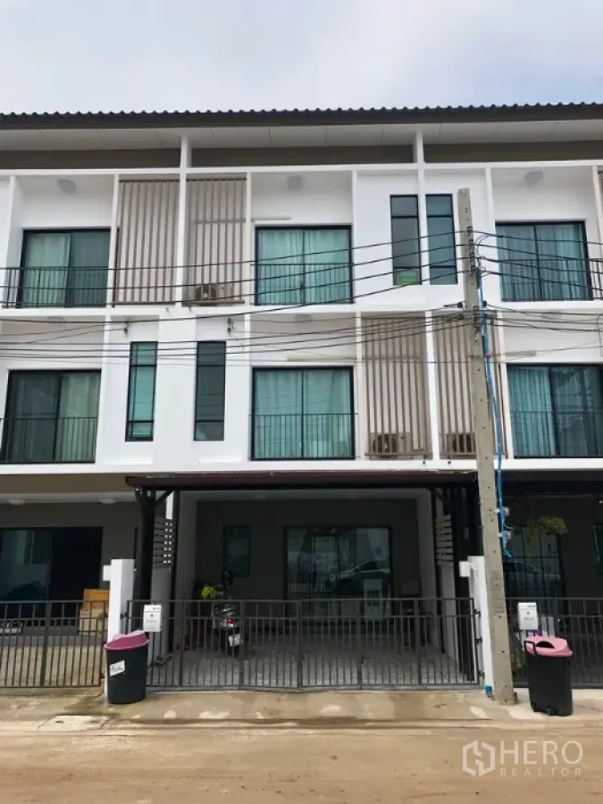 Townhouse for sale in Bang Kapi, Bangkok - Modern three-storey townhouse facade with gated covered carport and large windows.