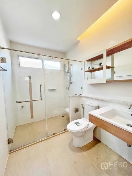 Detached House for rent in Prawet, Bangkok - Bathroom with glass-enclosed shower, vanity and shelving in warm neutral tones.