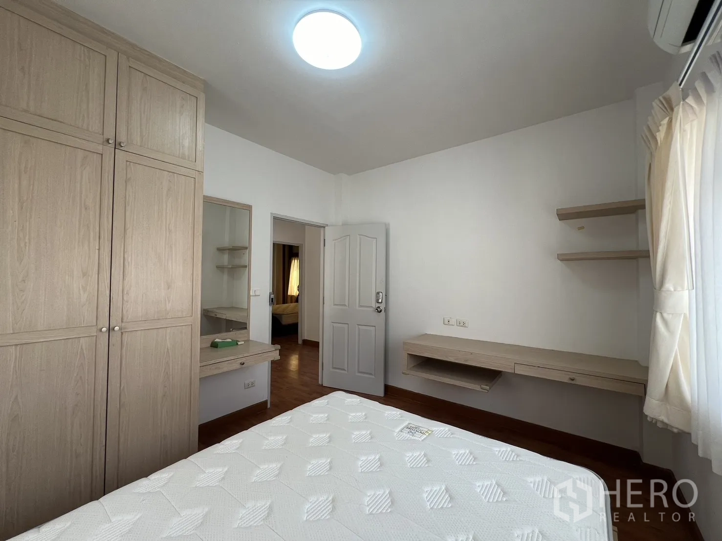 Detached House for rent in Bang Kapi, Bangkok - Bedroom with light wood built-in wardrobe, desk and shelving.