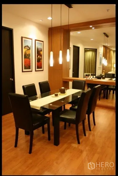 Condominium for rent or sale in Khlong Toei, Bangkok - Dining area with six-seat table, pendant lights and mirror wall on warm wood flooring.
