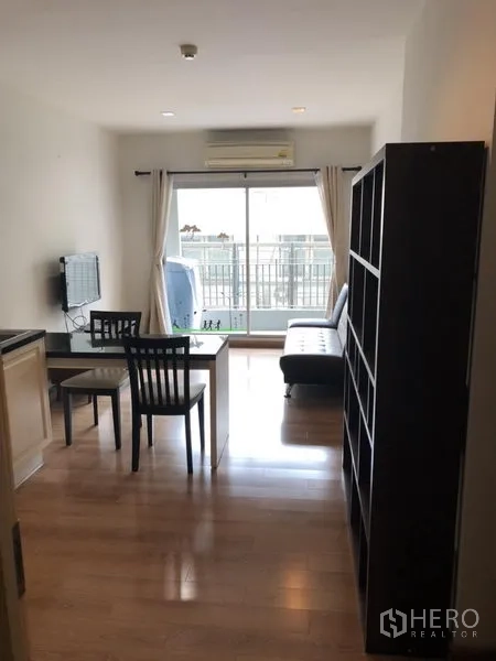 Condominium for rent in Pathum Wan, Bangkok - Bright living room with wood floors, sofa, dining table, TV and sliding doors to a balcony.