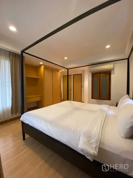 Condominium for rent in Watthana, Bangkok - Bedroom with four-poster bed, wardrobes, and a built-in dressing nook in warm wood cabinetry.