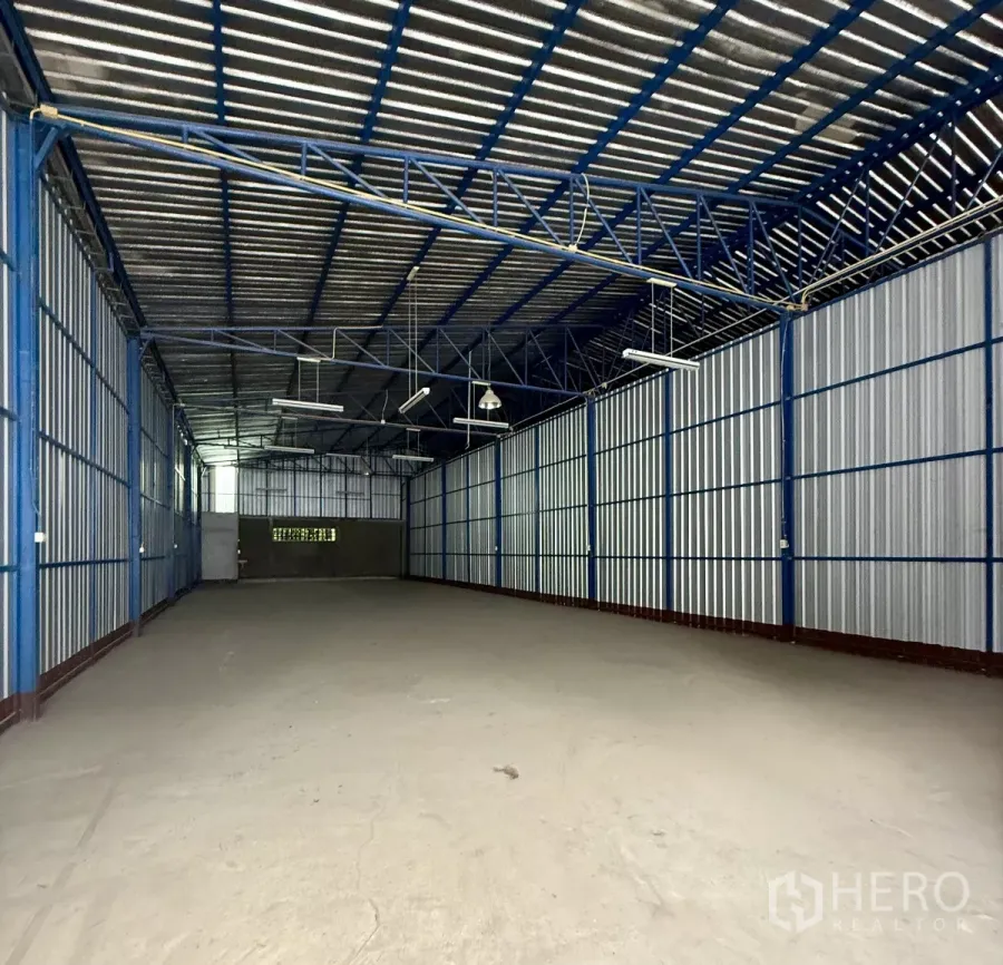 Warehouse for rent in Bueng Kum, Bangkok - Spacious warehouse interior with blue steel trusses, high gabled roof and concrete floor.