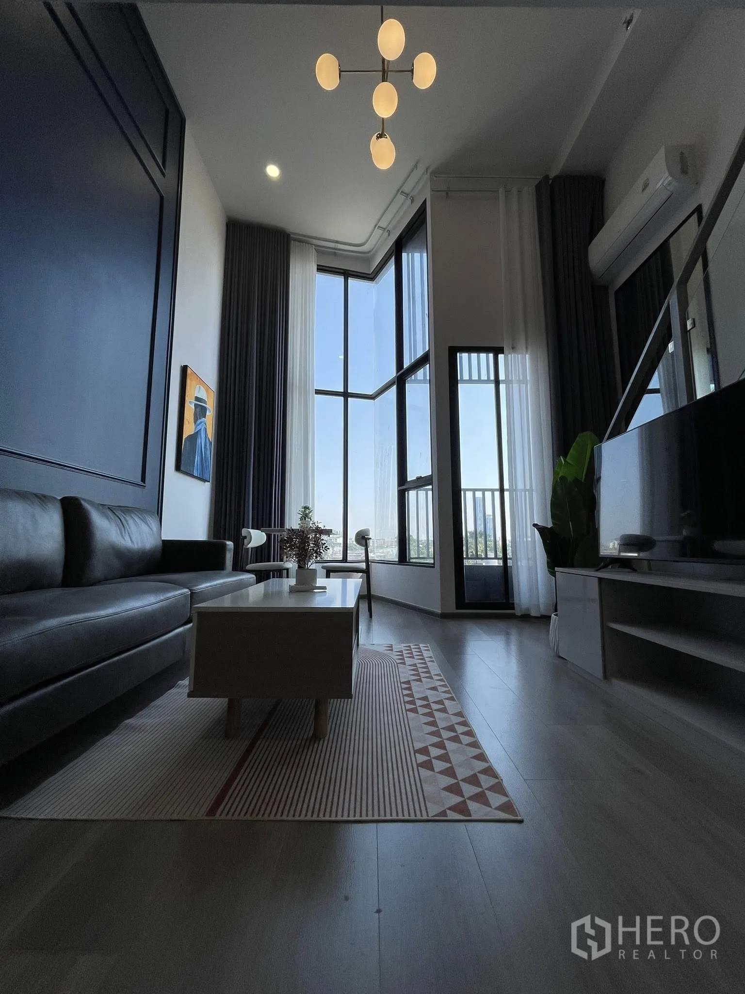 คอนโด for rent in Khlong Toei, Bangkok - ห้องนั่งเล่นสไตล์ลอฟต์ เพดานสูง โคมไฟดีไซน์ โซฟา ตู้ทีวี และหน้าต่างบานใหญ่