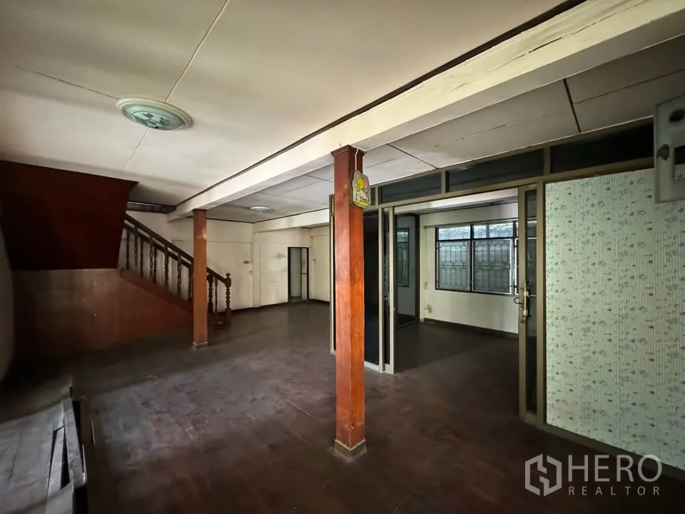 Detached House for rent or sale in Watthana, Bangkok - Ground-floor living area with wooden columns, staircase and dark wood floors.
