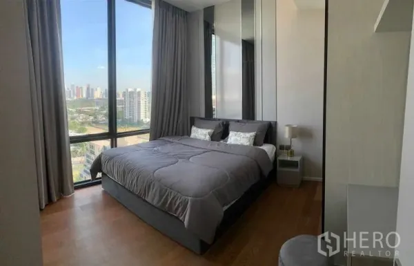 Condominium for rent in Pathum Wan, Bangkok - Bright bedroom in Pathum Wan condo for rent featuring large windows, city skyline views and wood flooring.