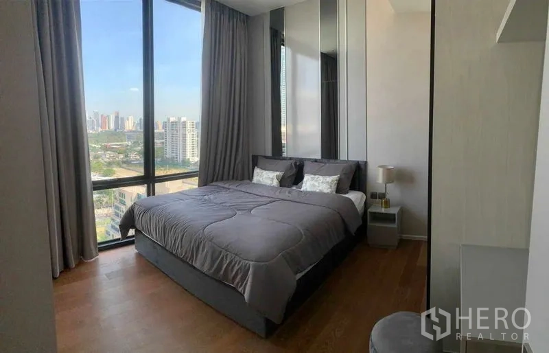 Condominium for rent in Pathum Wan, Bangkok - Bright bedroom in Pathum Wan condo for rent featuring large windows, city skyline views and wood flooring.