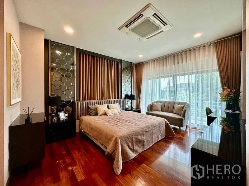 Detached House for rent in Bang Phli, Samut Prakan - Spacious master bedroom with balcony access, sofa seating and hardwood floors.
