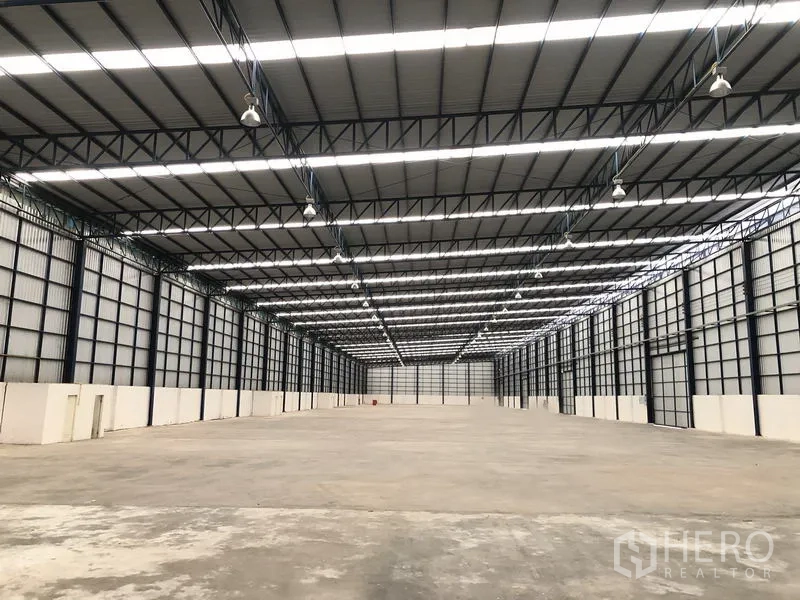 Factory for rent or sale in Phra Nakhon Si Ayutthaya - Symmetrical warehouse interior with polished concrete floor and LED high-bay lighting.