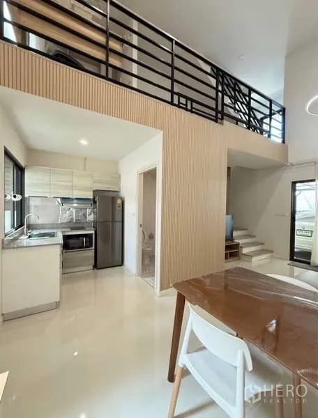 Townhouse for rent in Bang Phli, Samut Prakan - Dining zone and kitchen under the mezzanine with staircase leading up.