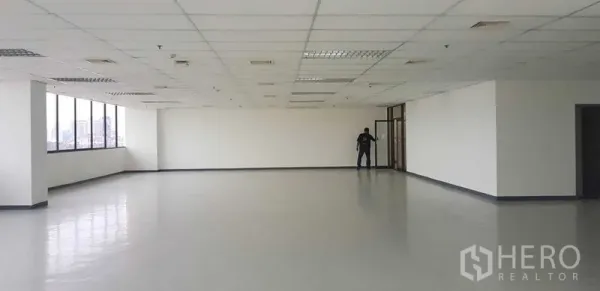 Office Space for rent in Khlong Toei, Bangkok - Spacious open-plan office floor with a long row of corner windows, city views, white walls, grid ceiling lights and ducted air-conditioning.