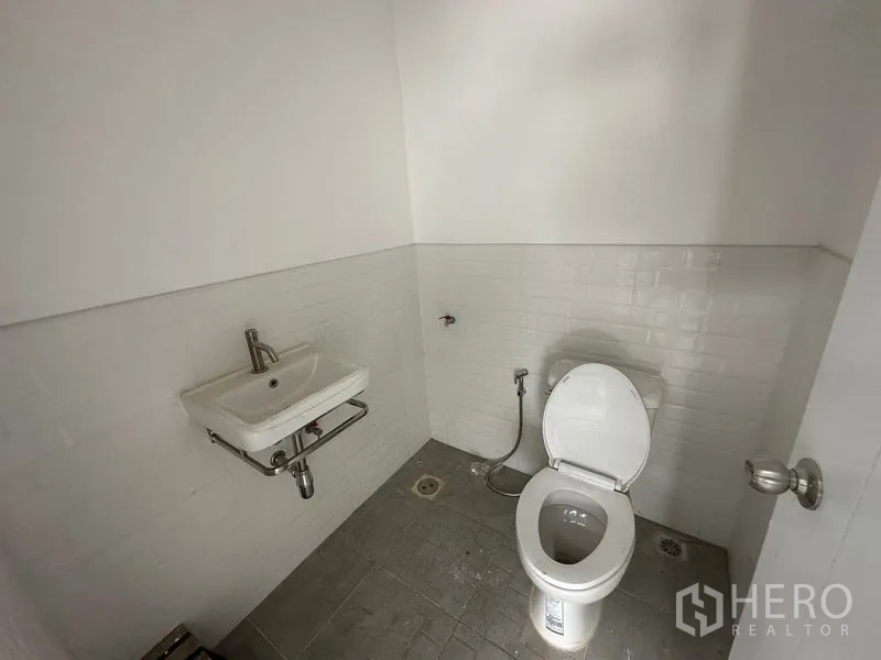 Warehouse for rent in Bang Phli, Samut Prakan - Clean restroom with gray floor tiles, white subway-tile walls and a corner hand basin.