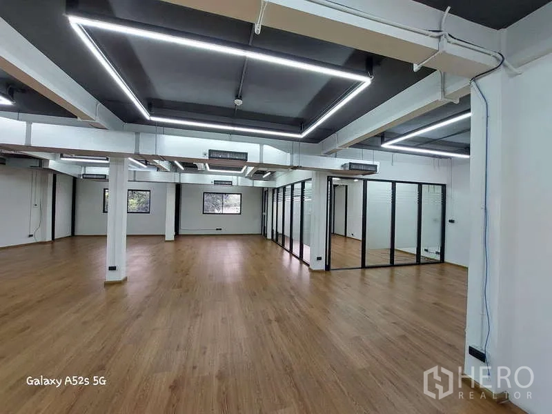 Office Space for rent in Khlong Toei, Bangkok - Open-plan office with LED ceiling panels, glass rooms and warm wood flooring.